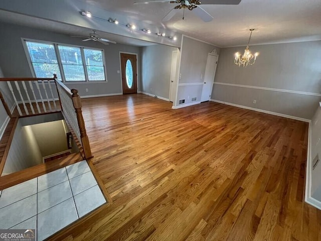 foyer with baseboards, wood finished floors, and ceiling fan with notable chandelier