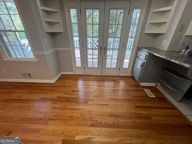 doorway to outside with visible vents, light wood-style flooring, baseboards, and french doors