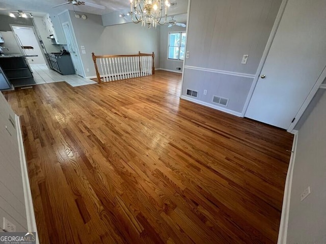 unfurnished dining area with visible vents, light wood finished floors, and ceiling fan with notable chandelier