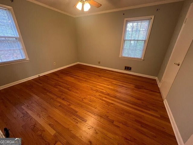 spare room with baseboards, ornamental molding, and wood finished floors