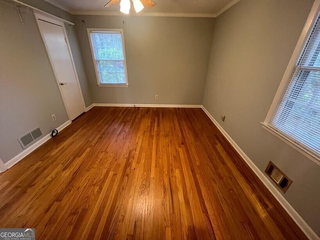 unfurnished bedroom featuring baseboards, ornamental molding, wood finished floors, and visible vents