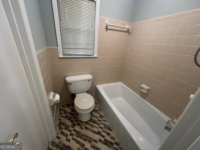 bathroom with tile walls, a wainscoted wall, and toilet