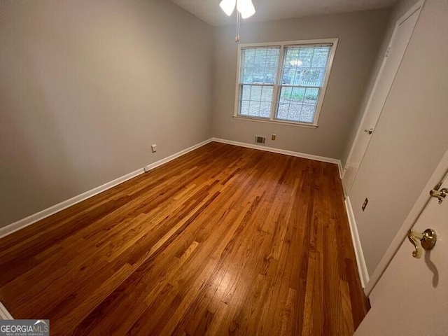 unfurnished bedroom with baseboards, dark wood finished floors, and visible vents