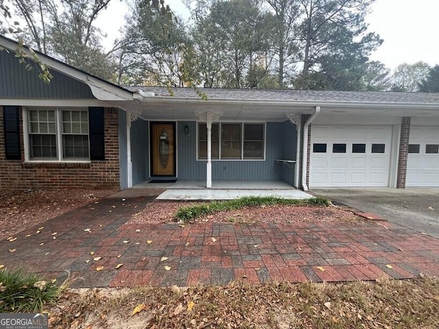 ranch-style house featuring a garage, a porch, driveway, and brick siding