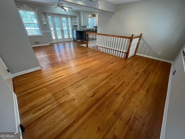 unfurnished living room featuring baseboards, a ceiling fan, wood finished floors, and visible vents