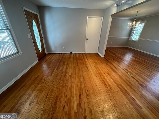 interior space featuring an inviting chandelier, baseboards, and wood finished floors