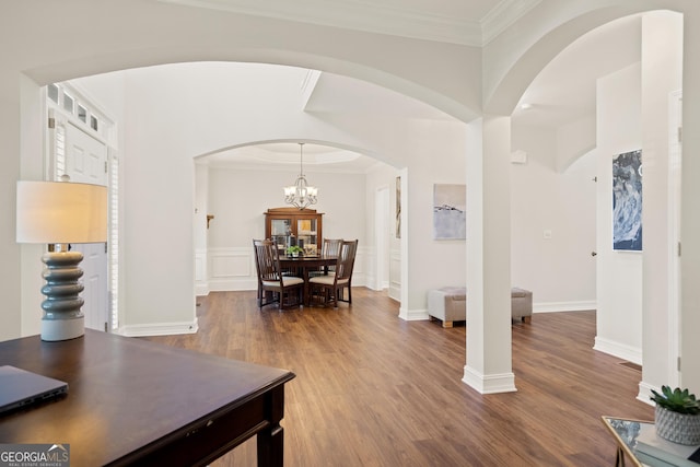 foyer featuring arched walkways, ornamental molding, wood finished floors, and a chandelier