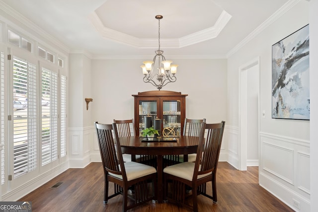 dining area featuring an inviting chandelier, dark wood-style flooring, a decorative wall, a wainscoted wall, and a tray ceiling