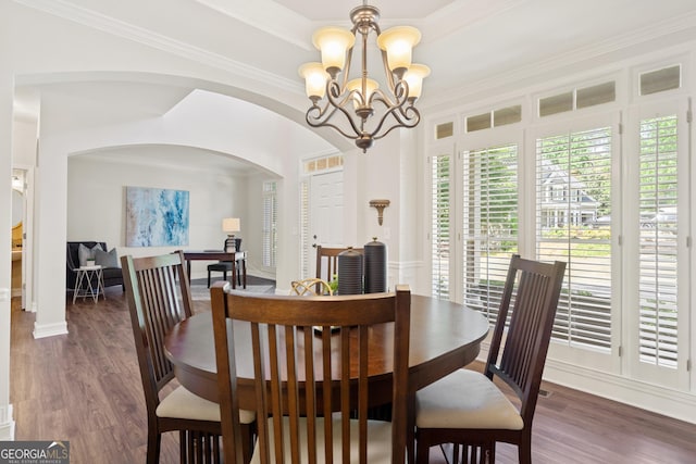 dining space with crown molding, arched walkways, wood finished floors, and a chandelier