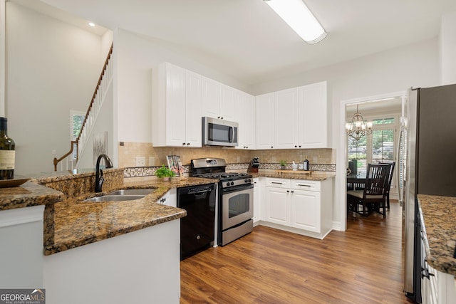 kitchen featuring a sink, appliances with stainless steel finishes, dark stone countertops, and wood finished floors