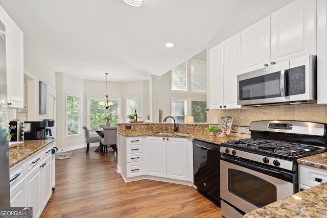 kitchen featuring appliances with stainless steel finishes, a sink, white cabinets, an inviting chandelier, and light wood-style flooring
