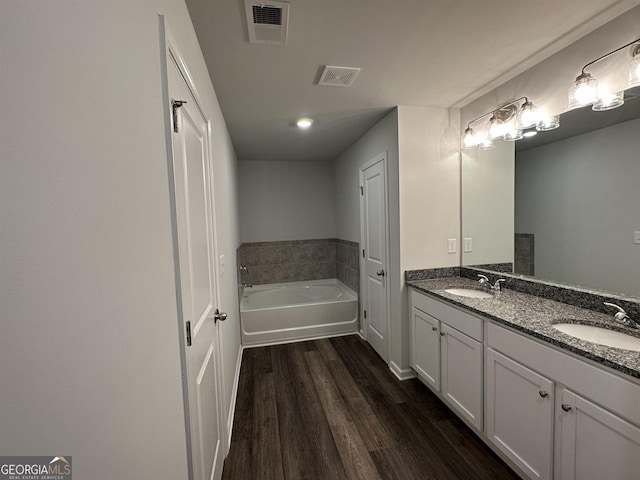 bathroom featuring double vanity, visible vents, a sink, and wood finished floors