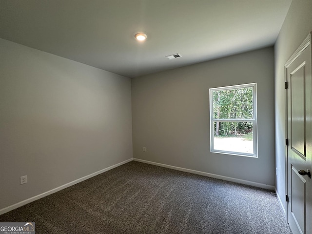empty room with dark carpet, baseboards, and visible vents