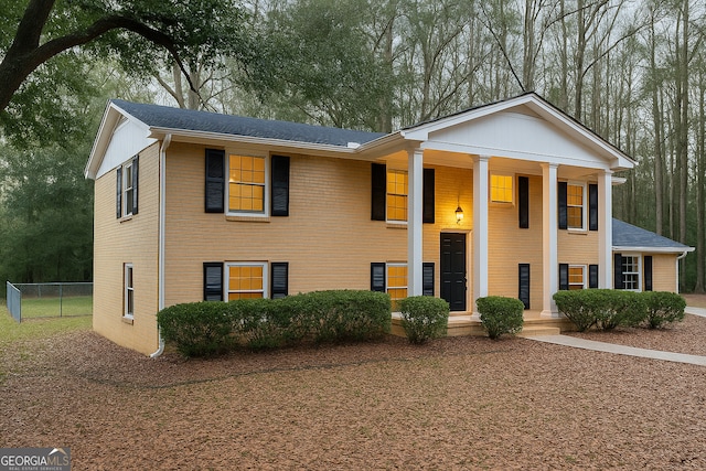 neoclassical home with fence, a shingled roof, and a porch