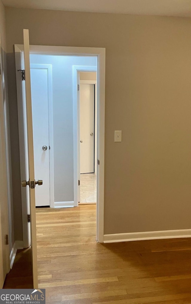 hall featuring light wood-type flooring and baseboards