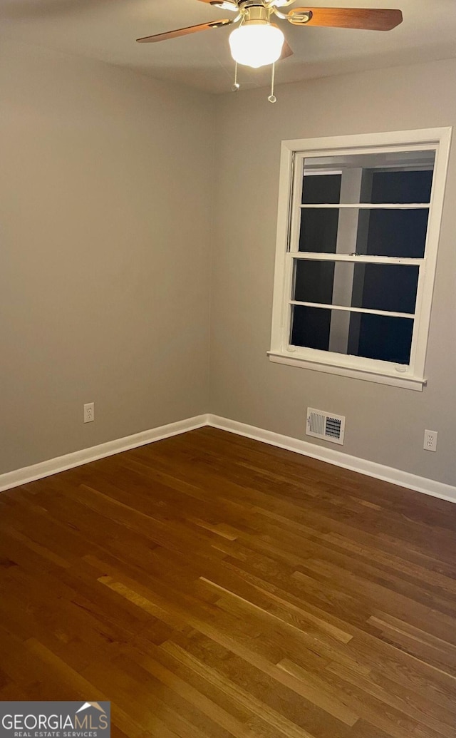 empty room featuring ceiling fan, wood finished floors, and baseboards