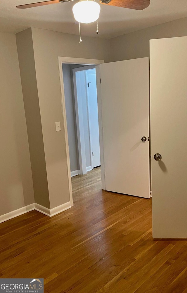 spare room featuring a ceiling fan, wood finished floors, and baseboards