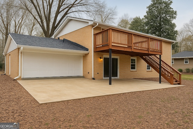 back of property with brick siding, a wooden deck, stairway, and an attached garage