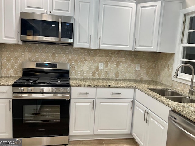kitchen with stainless steel appliances, a sink, and white cabinetry
