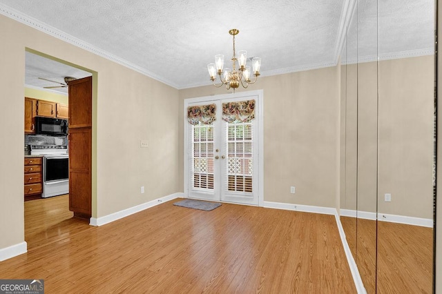 unfurnished dining area featuring light wood-style floors, a chandelier, baseboards, a textured ceiling, and ornamental molding
