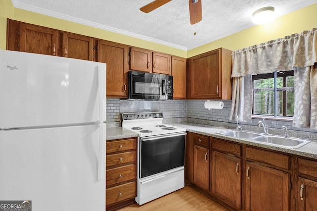 kitchen with white appliances, a sink, decorative backsplash, brown cabinetry, and a textured ceiling