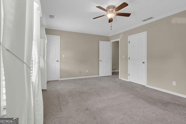 unfurnished bedroom with carpet floors, baseboards, ornamental molding, and a ceiling fan