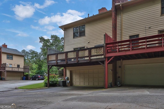 rear view of property featuring a garage, a chimney, and central air condition unit