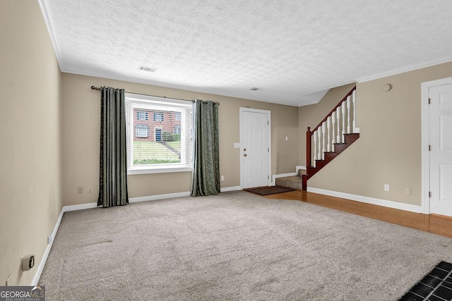 foyer entrance with stairs, a textured ceiling, baseboards, crown molding, and carpet flooring