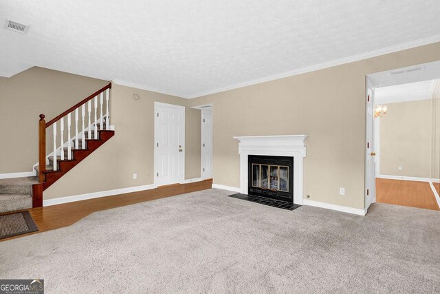 unfurnished living room with carpet floors, stairway, baseboards, a fireplace with flush hearth, and a textured ceiling