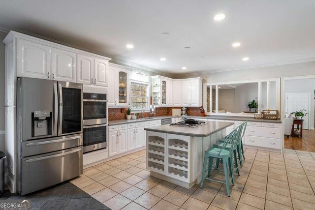 kitchen with a sink, glass insert cabinets, light tile patterned flooring, and stainless steel appliances