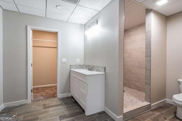 full bath with toilet, baseboards, walk in shower, a drop ceiling, and wood finish floors
