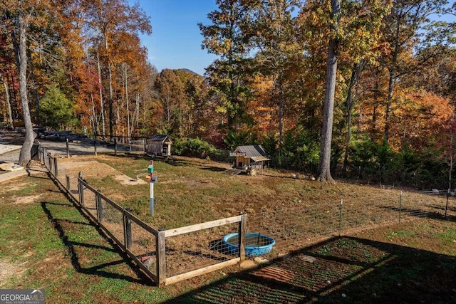 surrounding community with a yard, a forest view, and fence
