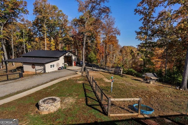 view of yard with an outdoor fire pit, fence, and an outbuilding
