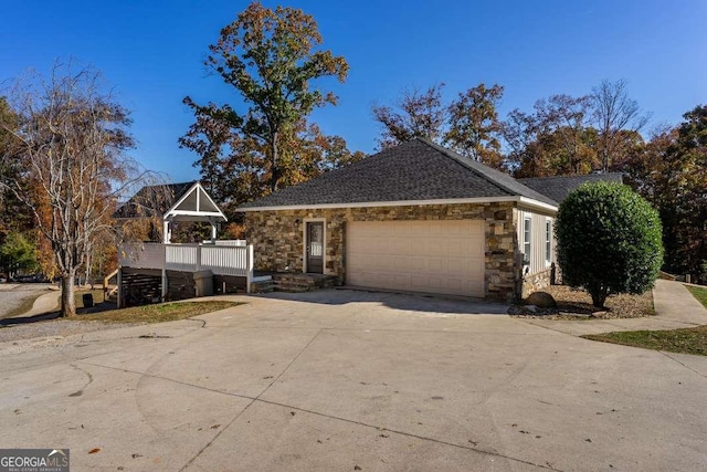 view of front of house featuring an attached garage, driveway, and stone siding