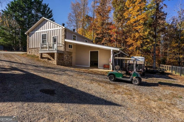 back of house with fence, board and batten siding, and stone siding