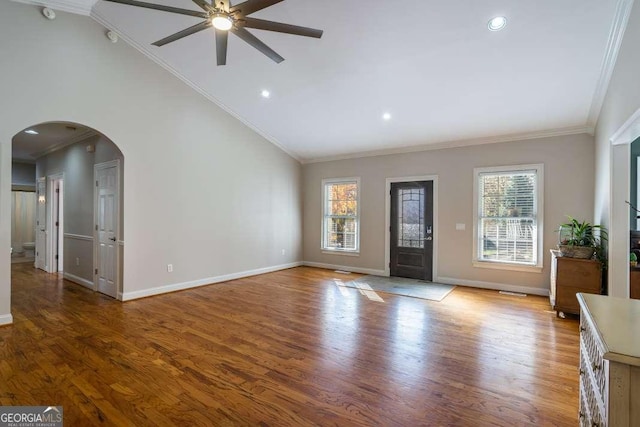 foyer entrance featuring a ceiling fan, arched walkways, vaulted ceiling, baseboards, and ornamental molding