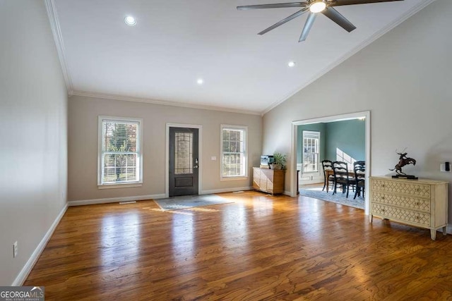 entrance foyer with a ceiling fan, baseboards, wood finished floors, vaulted ceiling, and ornamental molding