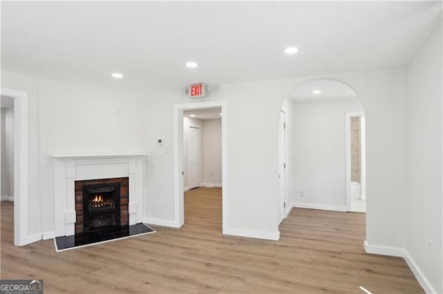 130 S Avenue SE, Marietta, GA 30060 - unfurnished living room with a brick fireplace, arched walkways, baseboards, and light wood-style floors