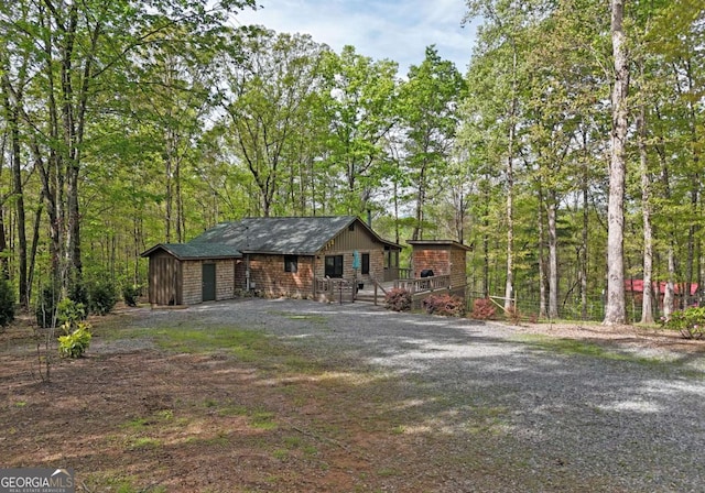 chalet / cabin with a deck, a storage unit, an outdoor structure, and gravel driveway
