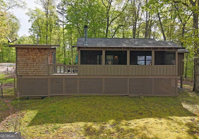 rear view of house featuring a yard, a deck, and a sunroom