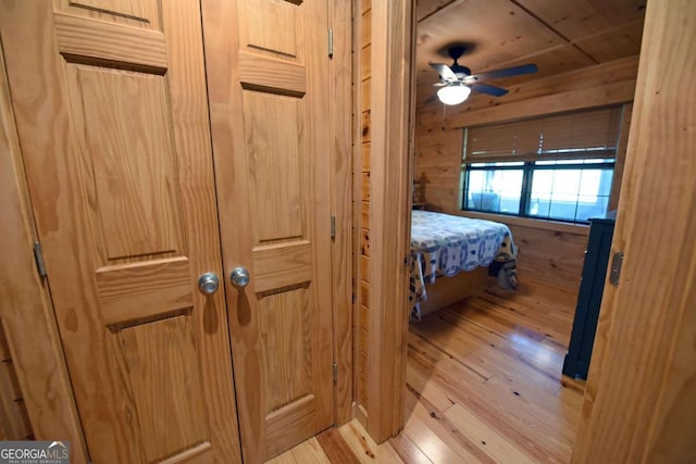 bedroom with light wood-style floors and wood walls