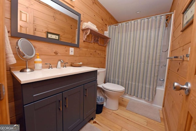 full bathroom with wooden walls, shower / bath combo, vanity, toilet, and wood finished floors