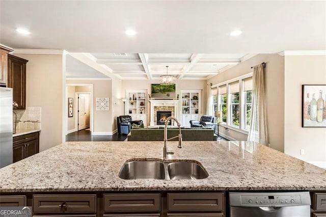 kitchen with dark brown cabinets, a sink, open floor plan, stainless steel dishwasher, and a center island with sink