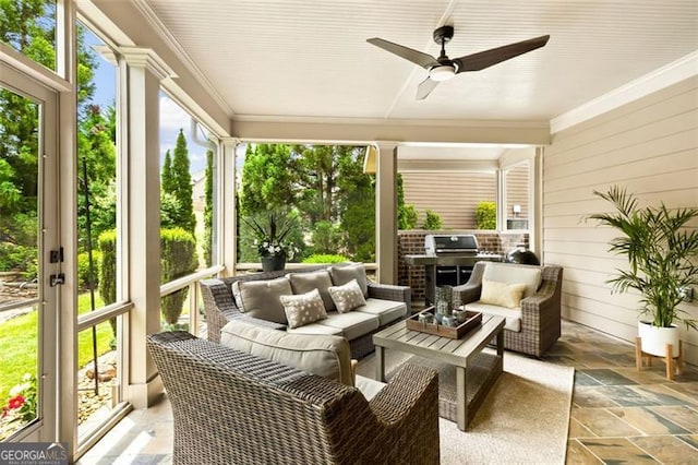 sunroom / solarium with stone tile flooring, ornamental molding, an outdoor hangout area, and a ceiling fan
