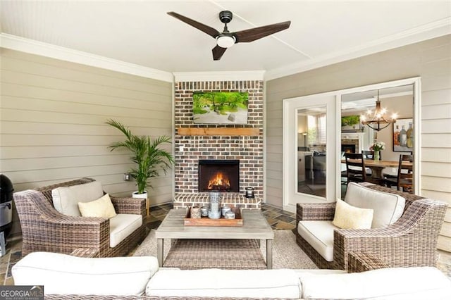 living room featuring wooden walls, ornamental molding, ceiling fan with notable chandelier, and an outdoor brick fireplace