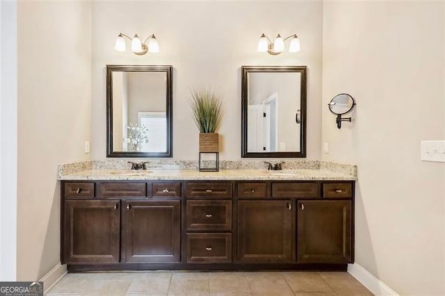 bathroom with double vanity, baseboards, a sink, and tile patterned flooring