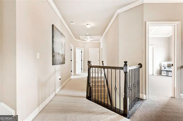 hall with baseboards, ornamental molding, carpet flooring, and an upstairs landing