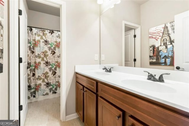 full bathroom with a sink, baseboards, tile patterned flooring, and double vanity