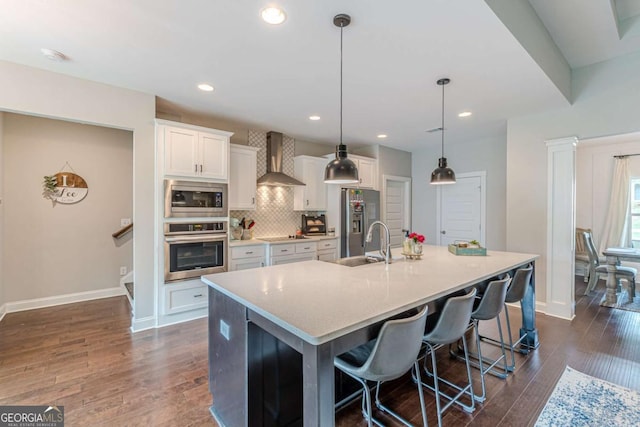 21 E Field St, Newnan, GA 30263 - kitchen featuring white cabinets, a kitchen island with sink, wall chimney exhaust hood, stainless steel appliances, and baseboards