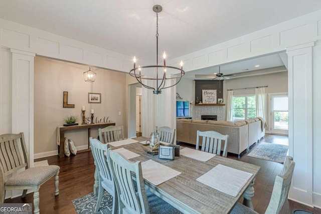 21 E Field St, Newnan, GA 30263 - dining room with baseboards, a fireplace, ceiling fan with notable chandelier, and dark wood-style flooring